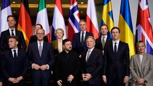 World leaders stand in front of a group of national flags