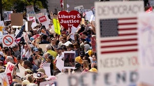 A crowd of protestors holding signs with various messages