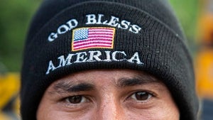 A person wears a hat saying "God Bless America" on the rim