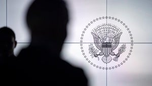 A silhouette of a person in front of the US seal