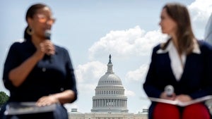 Two people talk in the foreground with the US Capitol building in the background