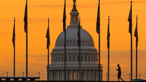 An early morning pedestrian is silhouetted against sunrise as he walks through the U.S. Flags on the National Mall and past the US Capitol Building in Washington.