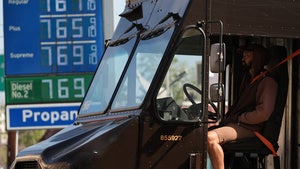 A UPS truck driver stands in transit as gasoline prices are advertised at over seven dollars a gallon at a gas station downtown Los Angeles Tuesday, March 3, 2026.