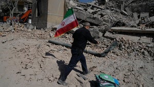  man carries an Iranian flag to place on the rubble of a police facility struck during the U.S.–Israeli military campaign in Tehran, Iran, Wednesday, March 4, 2026. 